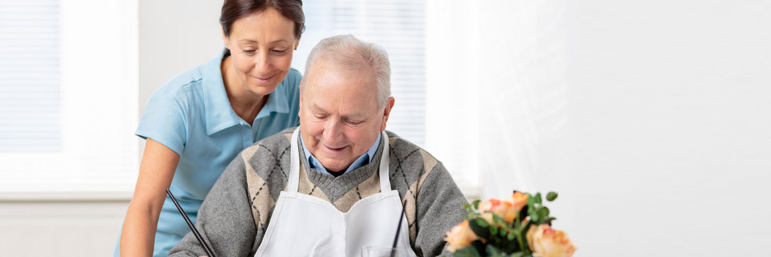 caregiver and elderly man cooking